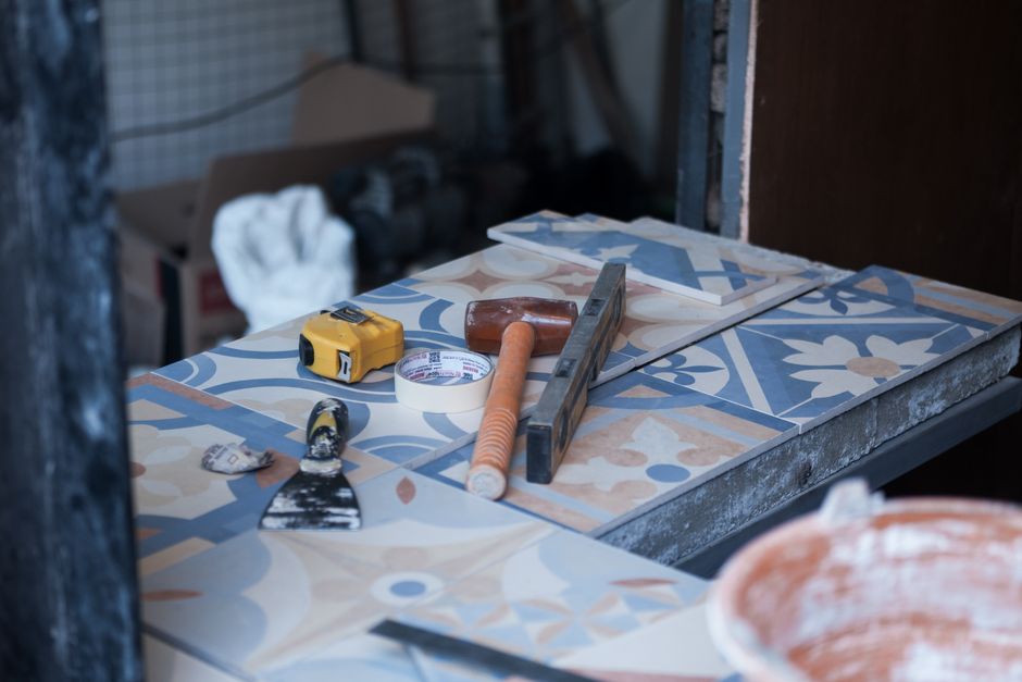 Tools and tiles on a construction site, ready for tiling work. Includes trowel, tape measure, and adhesive tape.